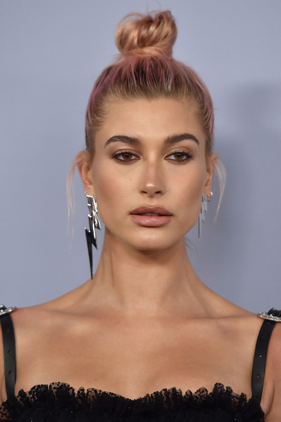 Hailey Bieber pembe topuz saçları iddialı küpeleriyle yakın plan portre fotoğrafı