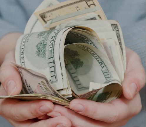 Avuçlarında bir tomar ABD doları olan eller
