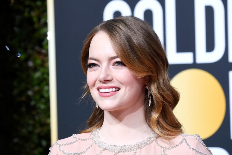 Emma Stone kırmızı halıda gülümseyen yüzü, dalgalı saçları ve küpeleri