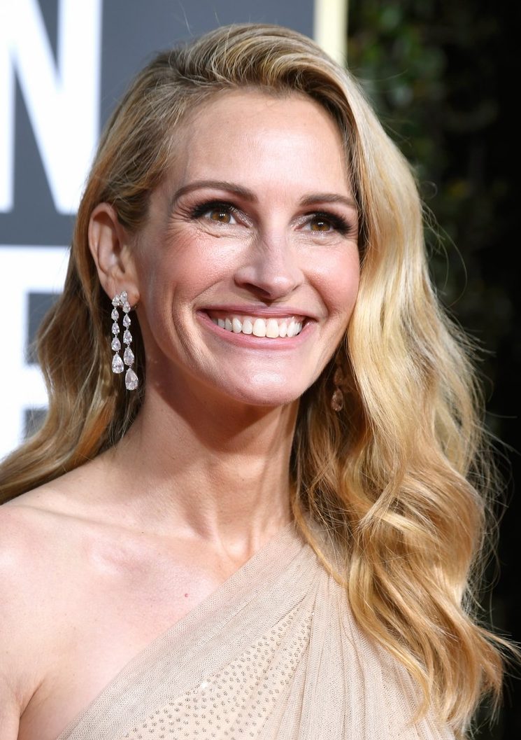 Bej elbise ve uzun küpeleriyle gülümseyen sarı saçlı Julia Roberts