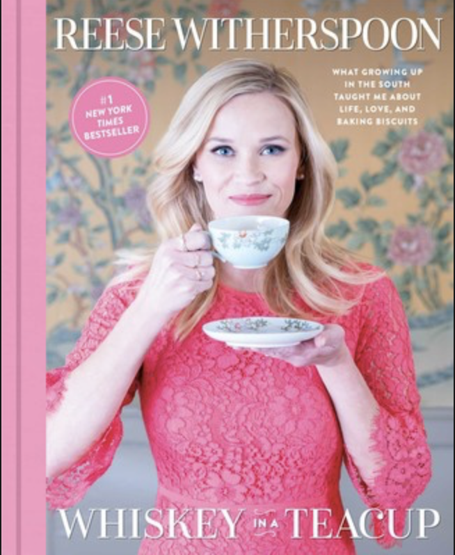 Reese Witherspoon pembe elbiseyle Whiskey in a Teacup kitap kapağında çay fincanı tutuyor