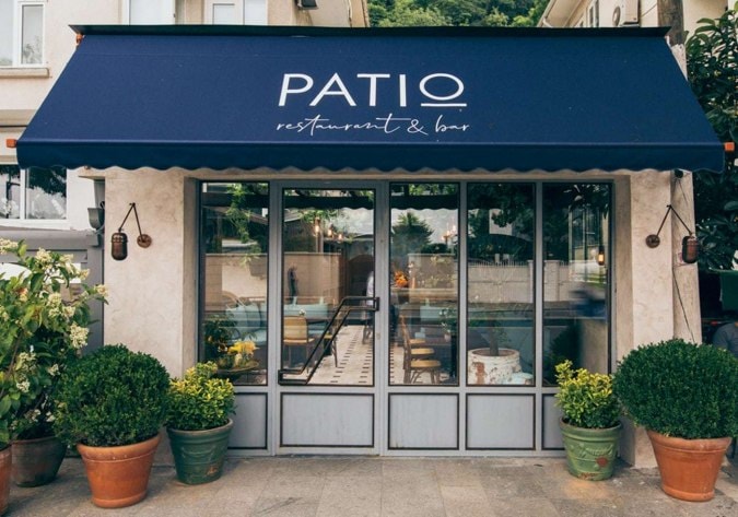 Mavi tenteli, cam pencereli ve saksı bitkili "PATIO" restoran dış görünümü