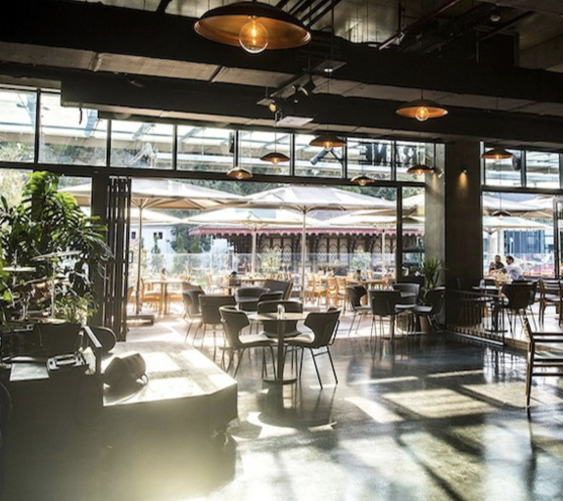 Modern restoran iç ve dış oturma alanları, büyük pencereler ve şemsiyeler