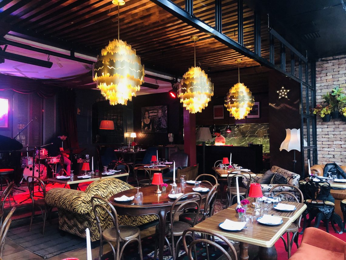 Altın rengi avizelerle aydınlatılmış canlı müzik mekanı restoran iç görünümü