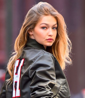 Gigi Hadid sarı saçları ve H harfli bomber ceketiyle omzundan bakıyor