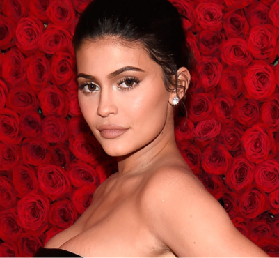 Kylie Jenner kırmızı güllerle kaplı duvarda makyajlı ve şık bir poz