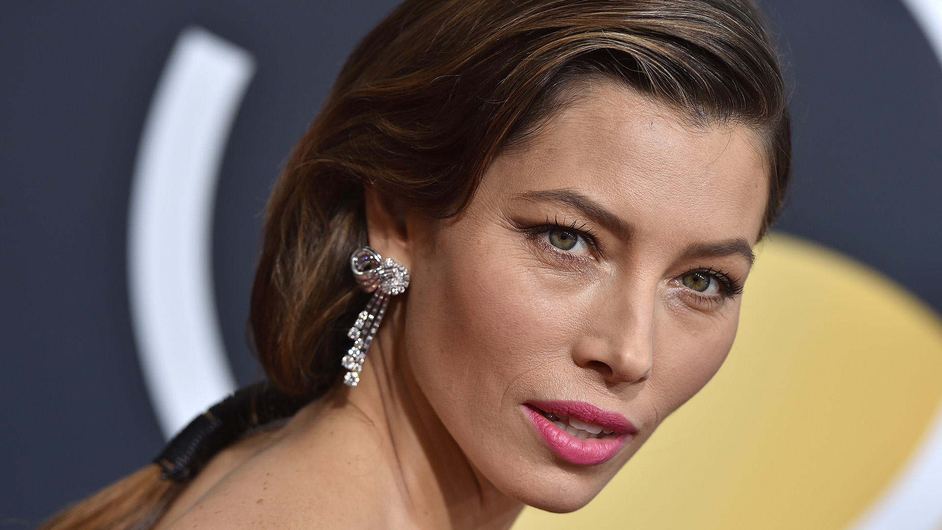 Jessica Biel'in parlak pembe ruju ve sallantılı küpesiyle yakın çekim portresi