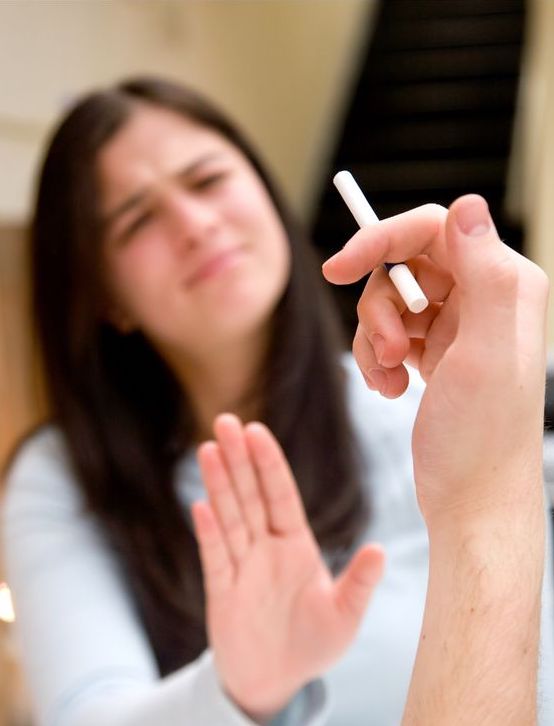 Kadın, uzatılan sigarayı eliyle itiyor, yüzünde hoşnutsuz bir ifade