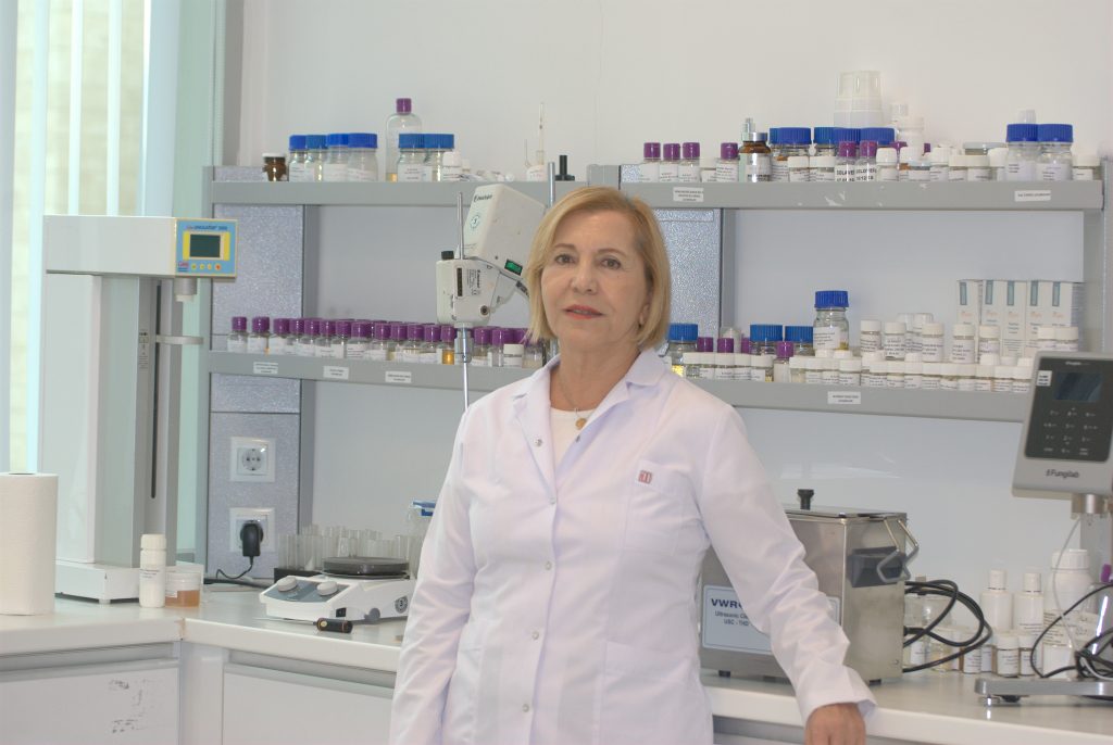 Laboratuvarda bilimsel ekipman ve şişelerle duran beyaz önlüklü kadın