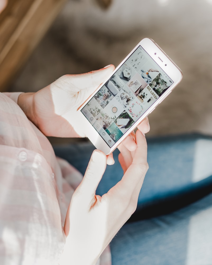Eller bir akıllı telefonu tutuyor ekranda sosyal medya görselleri var