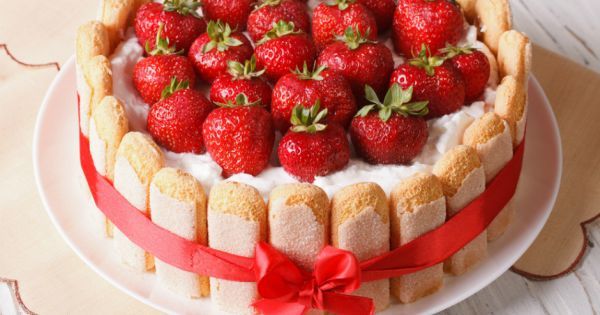 Çilekli Charlotte pastası etrafı bisküvi ve kırmızı kurdeleyle sarılı