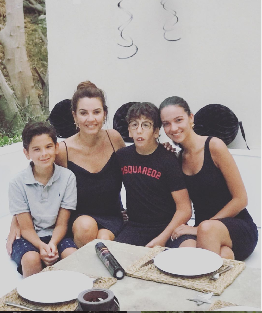 Mutlu bir aile masada oturmuş, gülümseyen anne ve üç çocuğu