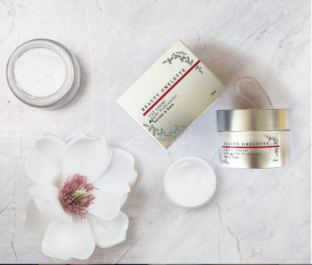 Probiyotikli Beauty Omelette yüz kremi kutusu ve kavanozları mermer üzerinde