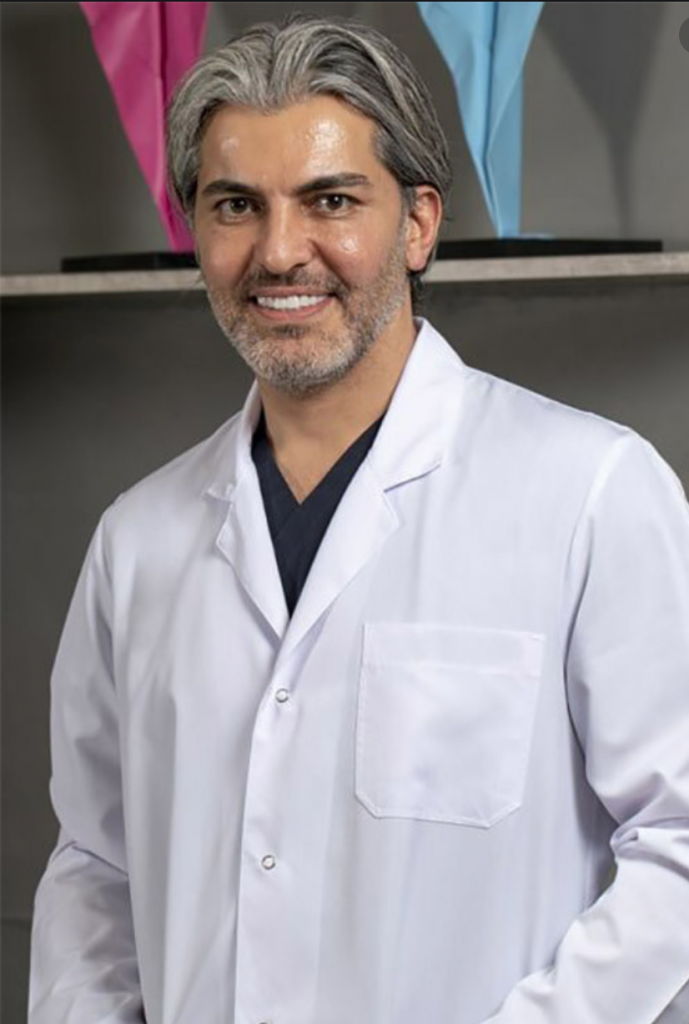 Gülümseyen beyaz önlüklü gri saçlı ve sakallı erkek doktor portresi