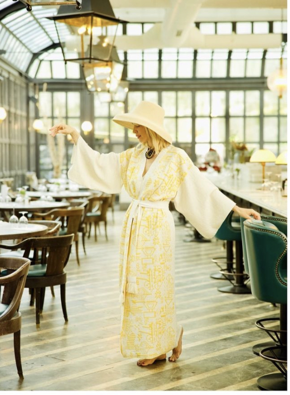 Sarı kaftan ve şapkalı kadın şık bir restoranda zarifçe duruyor