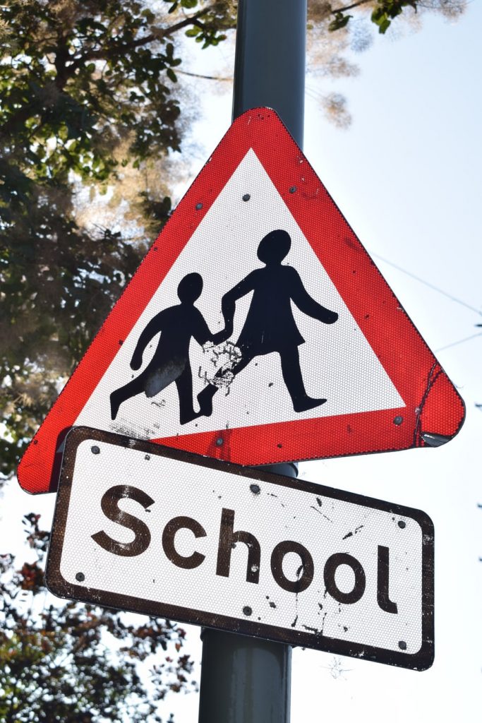 Eskimiş okul yolu işareti, üzerinde çocuk siluetleri ve "School" yazısı