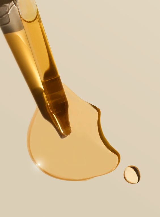 Damlalıktan bej bir zemine damlayan parlak, altın rengi serum