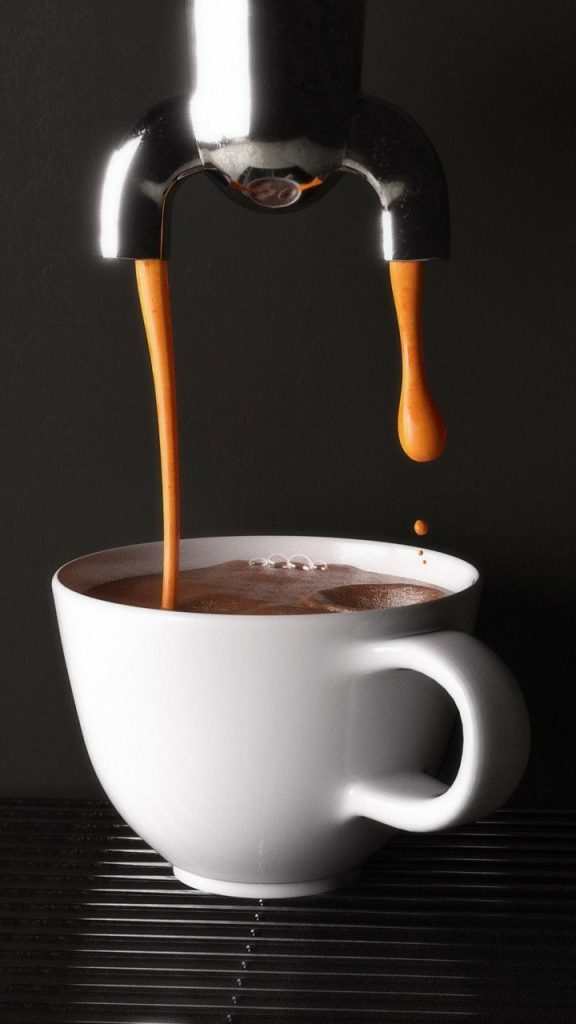 Espresso makinesinden beyaz fincana dolan yoğun kahve akışı