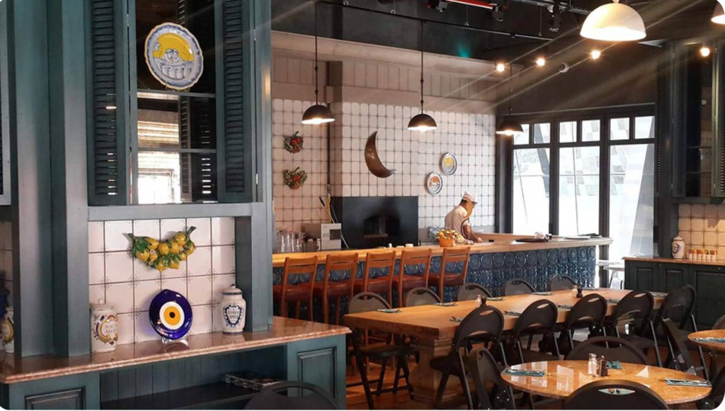 Akdeniz esintili bir restoranda bar masalar ve çalışan bir şef