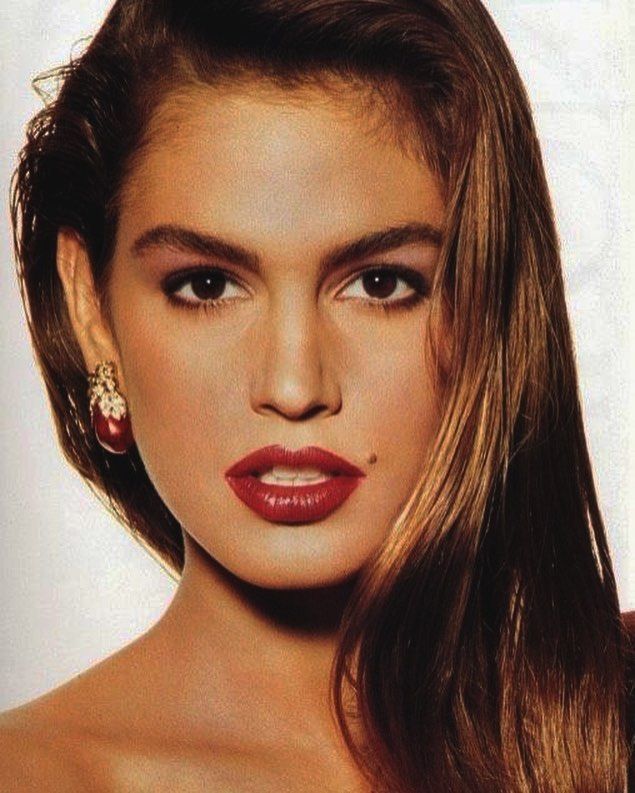 Cindy Crawford'ın ikonik benli, kırmızı rujlu ve kahverengi saçlı yakın çekim portresi