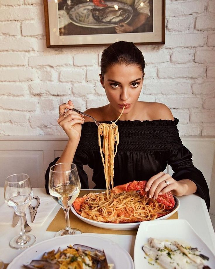 Siyah bluzlu kadın büyük bir tabaktan ıstakozlu spagetti yiyor