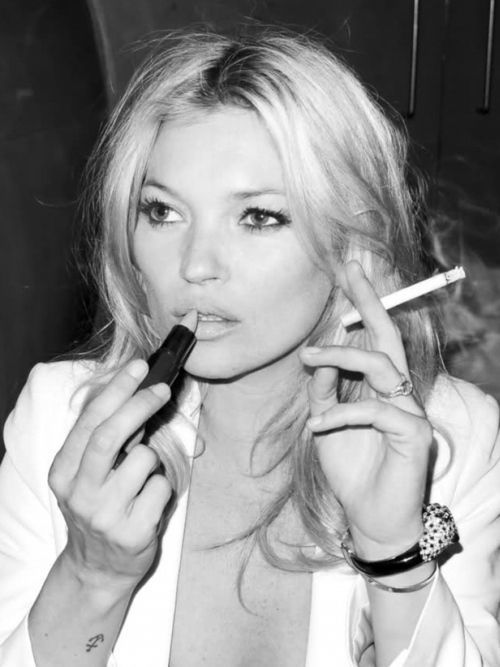 Kate Moss ruj sürerken sigara tutan siyah beyaz fotoğraf