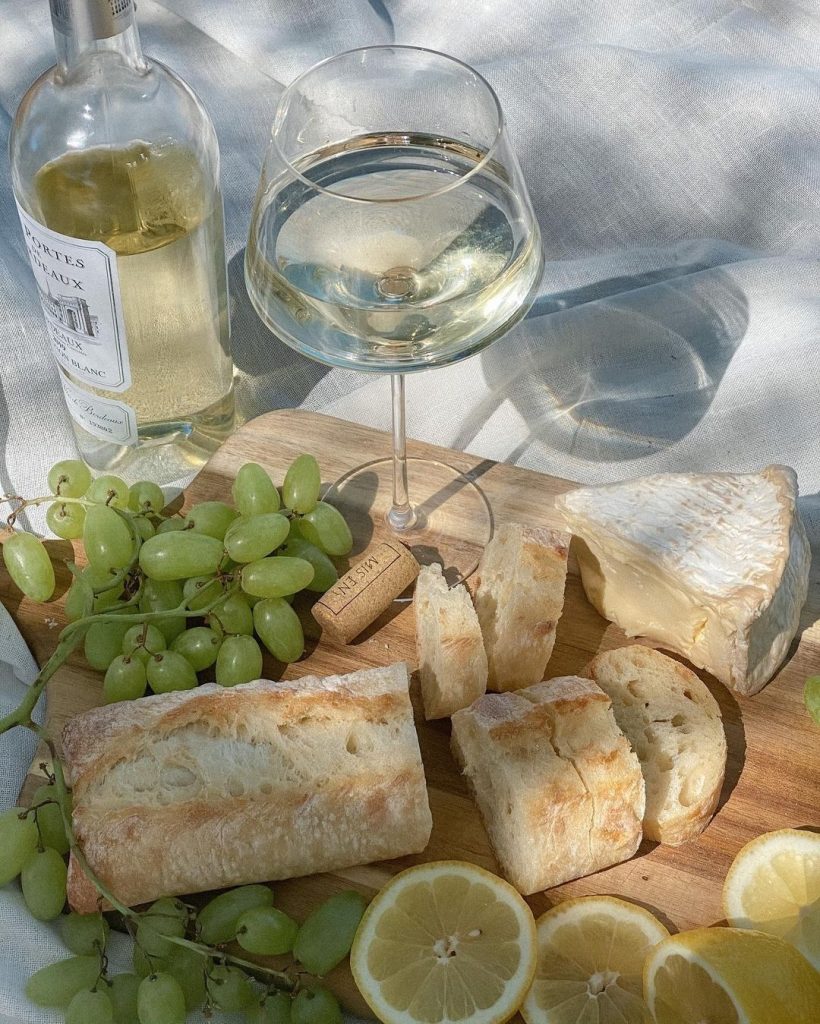 Beyaz şarap şişesi kadehi üzüm peynir ekmek ve limon dilimleri