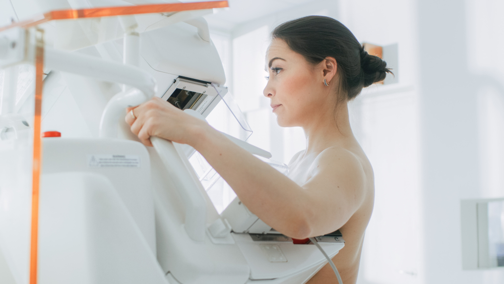 Bir kadın tıbbi cihazla meme kanseri taraması için mamogram çektiriyor