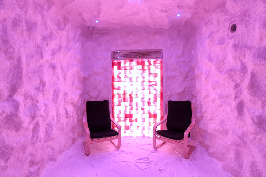 Pembe ışıklı tuz odası, iki sandalye ve aydınlatmalı tuz tuğlası panel