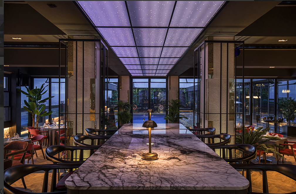Modern bir restoranın mermer tezgahı yıldızlı mor tavanı ve havuz manzarası