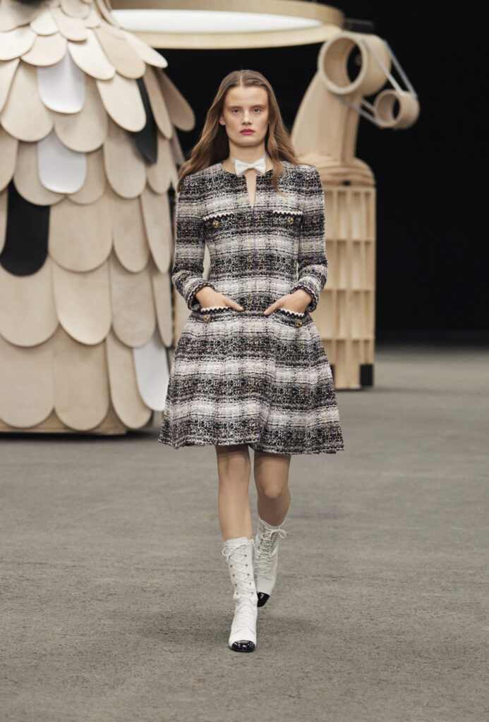 Bir model, tweed elbise ve botlarla podyumda yürüyor