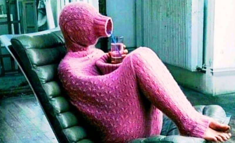 Pembe örgüden bütün vücut giysisi giymiş kişi içecek içerken
