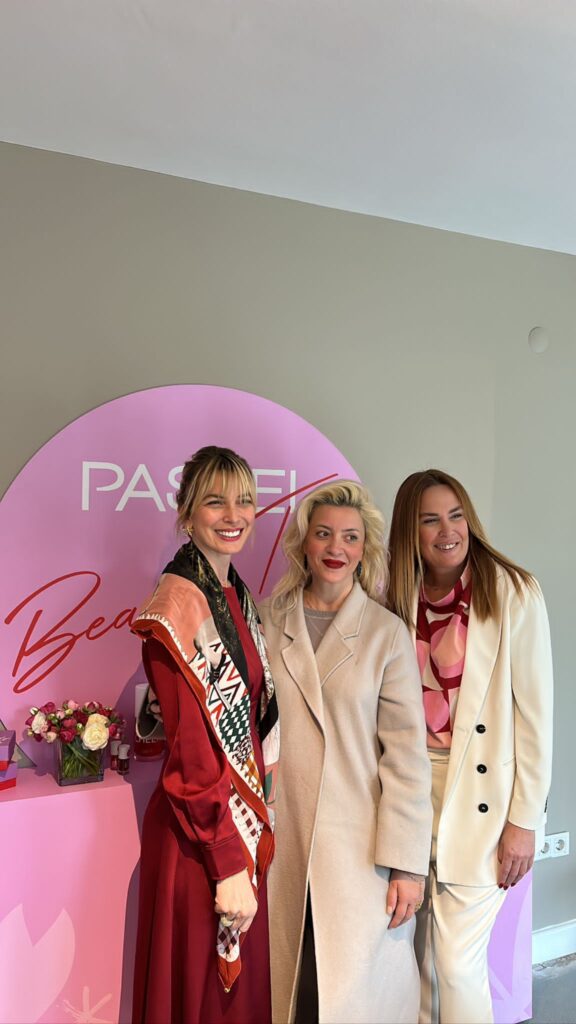 Pembe "PASTEL Beauty" tabelası önünde poz veren üç kadın