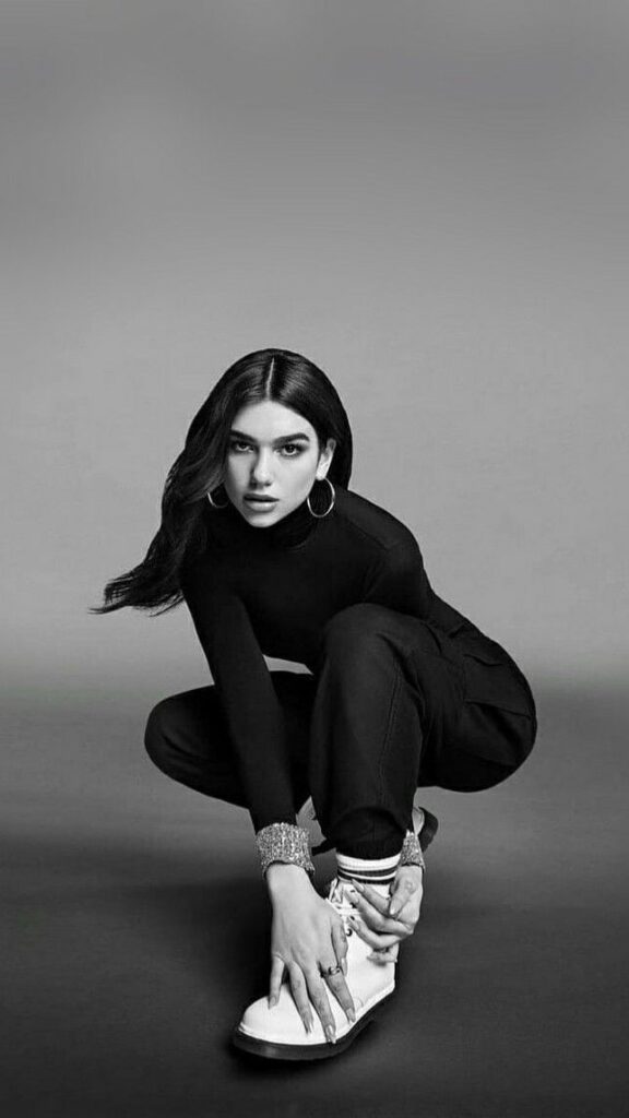 Dua Lipa siyah beyaz stüdyoda çömelmiş kameraya bakıyor