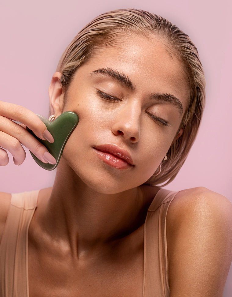Gua sha ile yüz masajı yapan kadın cilt bakımı rutini