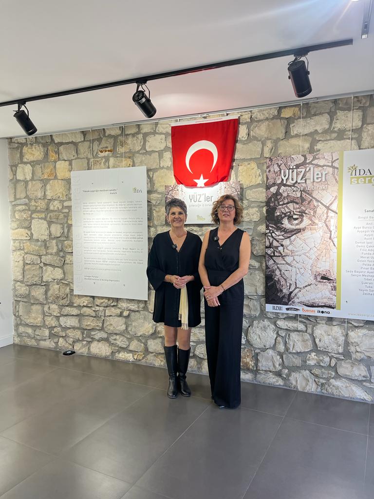 İki kadın sanat sergisinde Türk bayrağı ve posterlerin önünde
