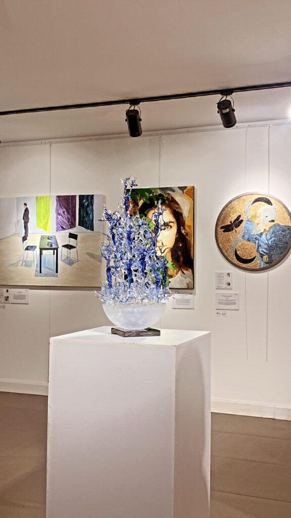 Sanat galerisinde cam heykel, portre ve diğer tablolar sergileniyor