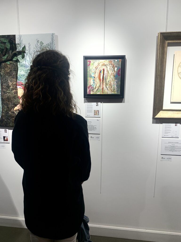 Sanat galerisinde tablolara bakan arkası dönük kıvırcık saçlı bir kadın