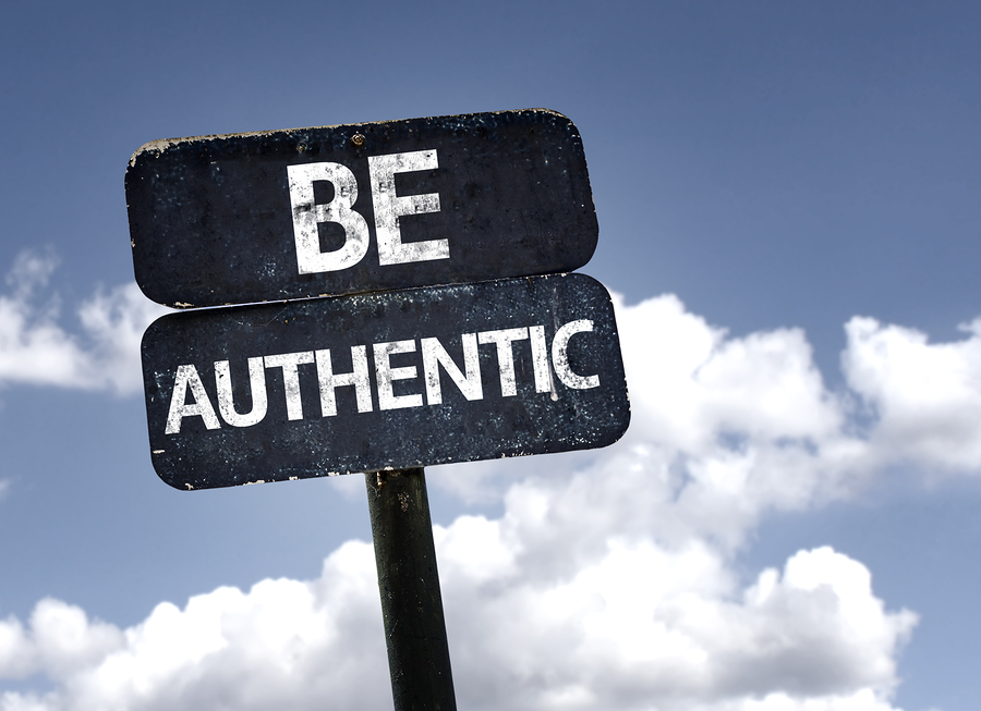 Mavi gökyüzü ve bulutlar önünde "BE AUTHENTIC" yazan eski bir işaret