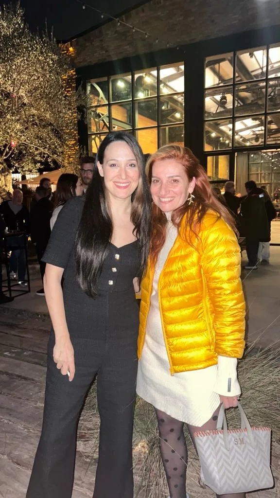 Gülümseyen iki kadın gece etkinlikte dışarıda duruyor