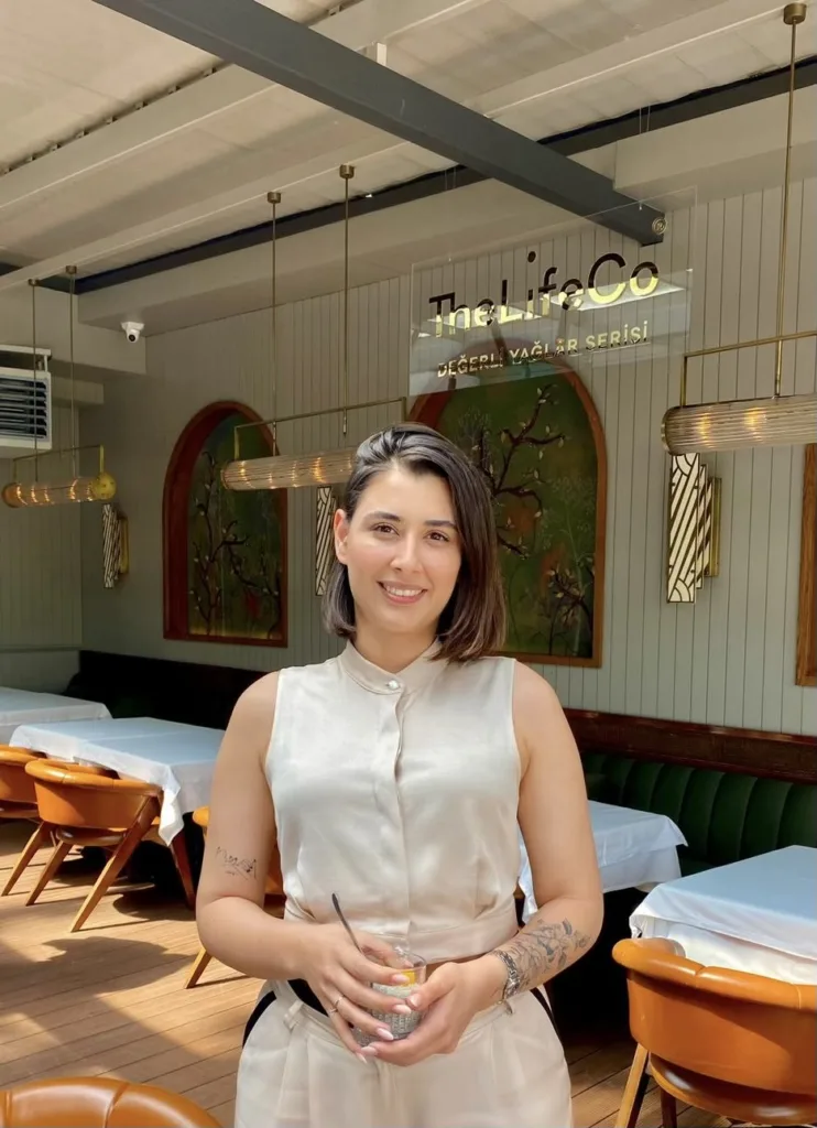 The LifeCo restoranında elinde içecek tutan gülümseyen kısa saçlı kadın