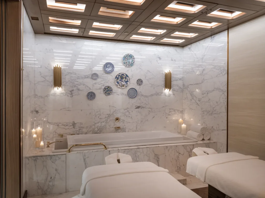 Lüks spa odası, mermer duvarlar, jakuzi, masaj masaları ve dekoratif tabaklar