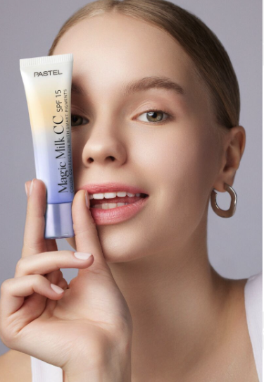 Yüzüne yakın Pastel Magic Milk CC SPF 15 tutan genç kadın
