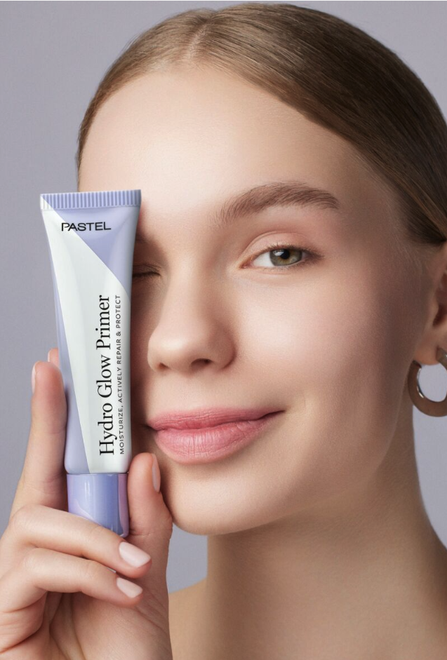 Pastel Hydro Glow Primer tutan gülümseyen genç kadın göz kırpıyor