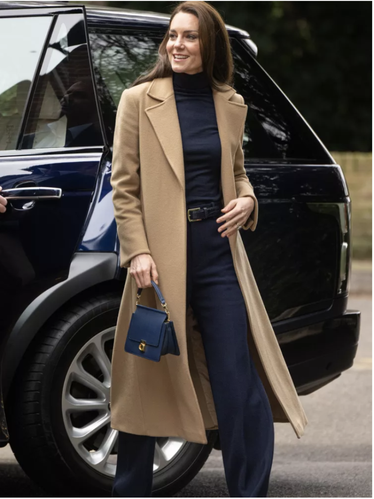 Kate Middleton deve tüyü kaban, lacivert giysiler ve çanta ile arabanın yanında