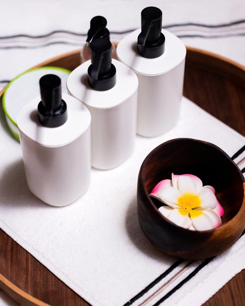 Ahşap tepside spa ürünleri, havlu ve kasede tropik çiçek