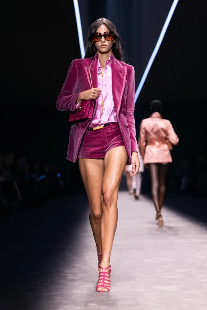 Podyumda pembe kadife ceket şort takım giyen kadın model