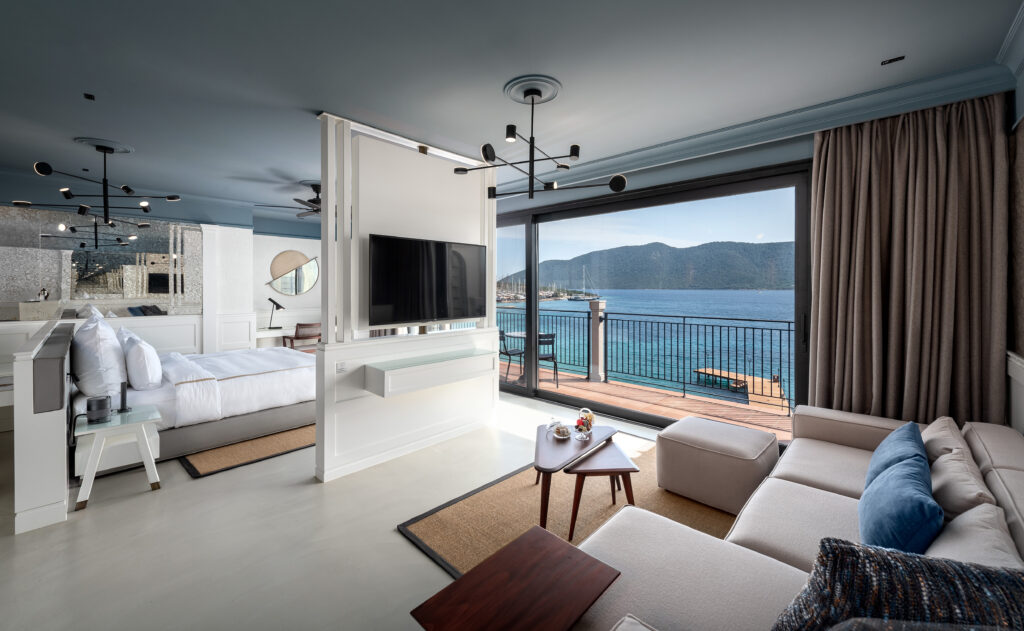 Panoramik deniz manzaralı modern şık otel süiti yatak ve oturma alanı