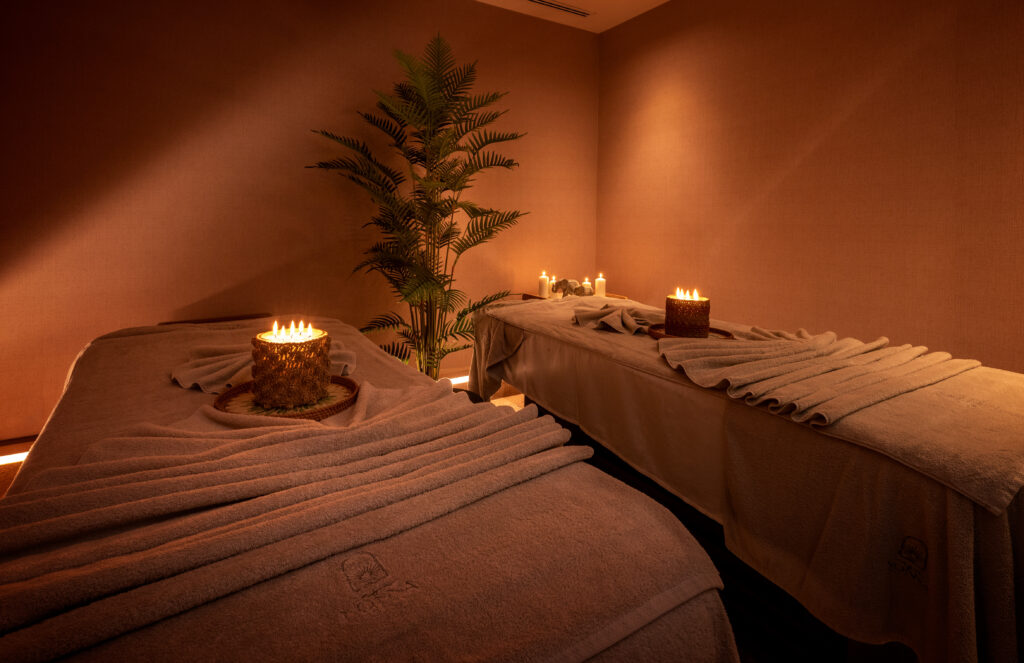 Mum ışığı ve bitkilerle huzurlu bir spa odasında iki masaj yatağı