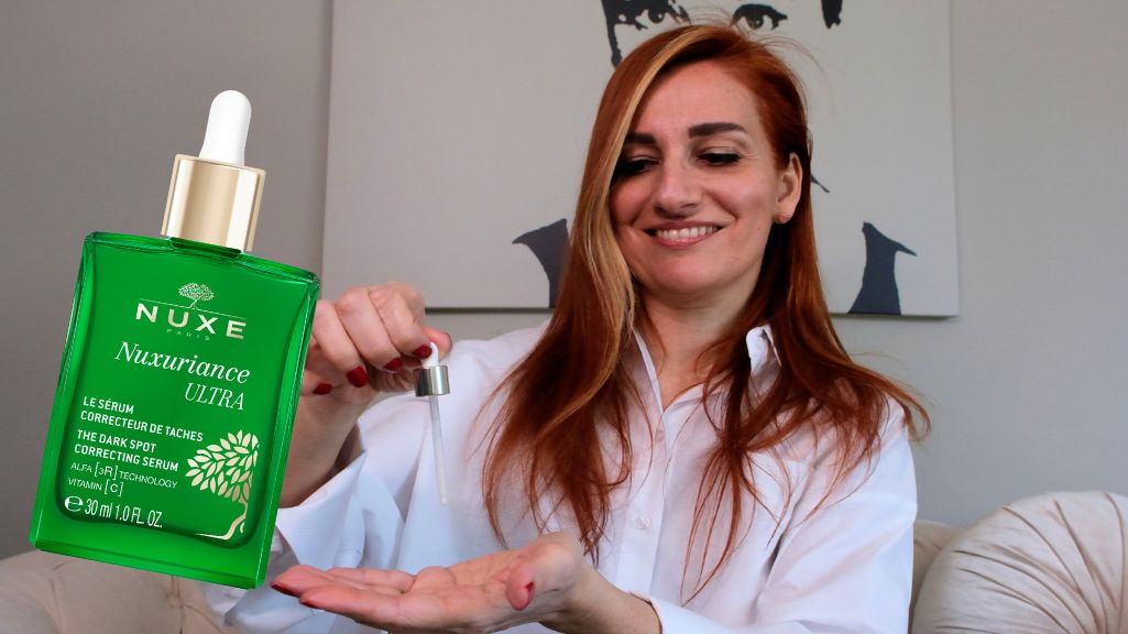 Gülümseyen kadın Nuxe Nuxuriance Ultra koyu leke serumunu eline damlatıyor